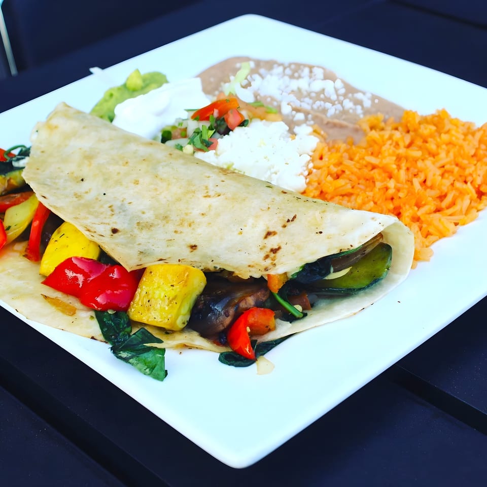 A colorful Angus Grill & Cantina fajita burrito with rice, beans, guacamole, and sour cream.